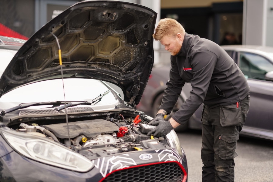 A mechanic taking readings from under a cars bonnet